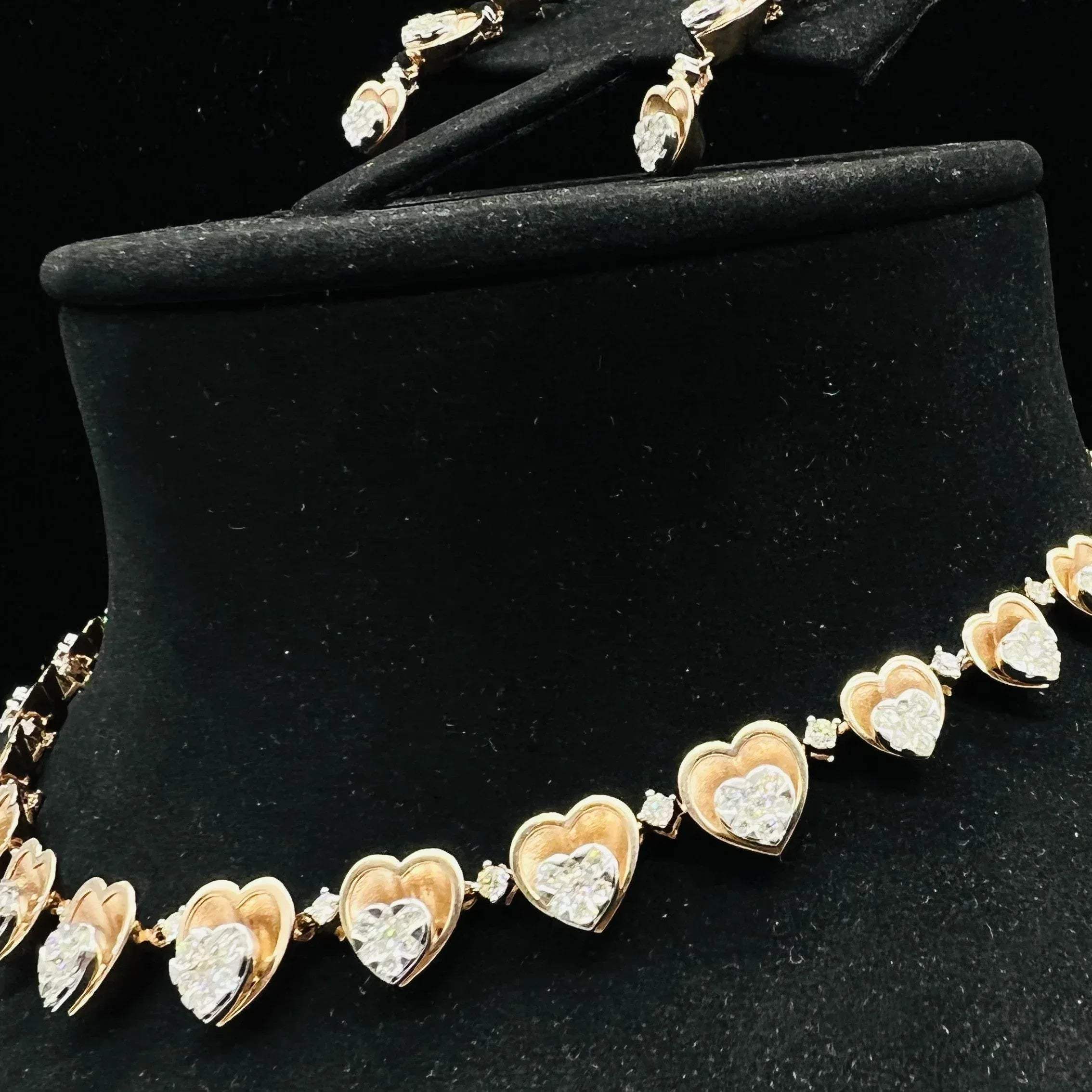 A gold necklace with round-cut diamond pendants and coordinating earrings, displayed on a black mannequin bust.