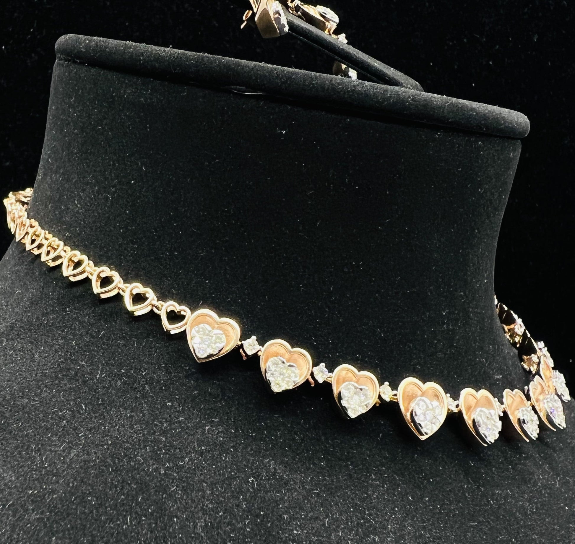 A gold necklace with round-cut diamond pendants and coordinating earrings, displayed on a black mannequin bust.
