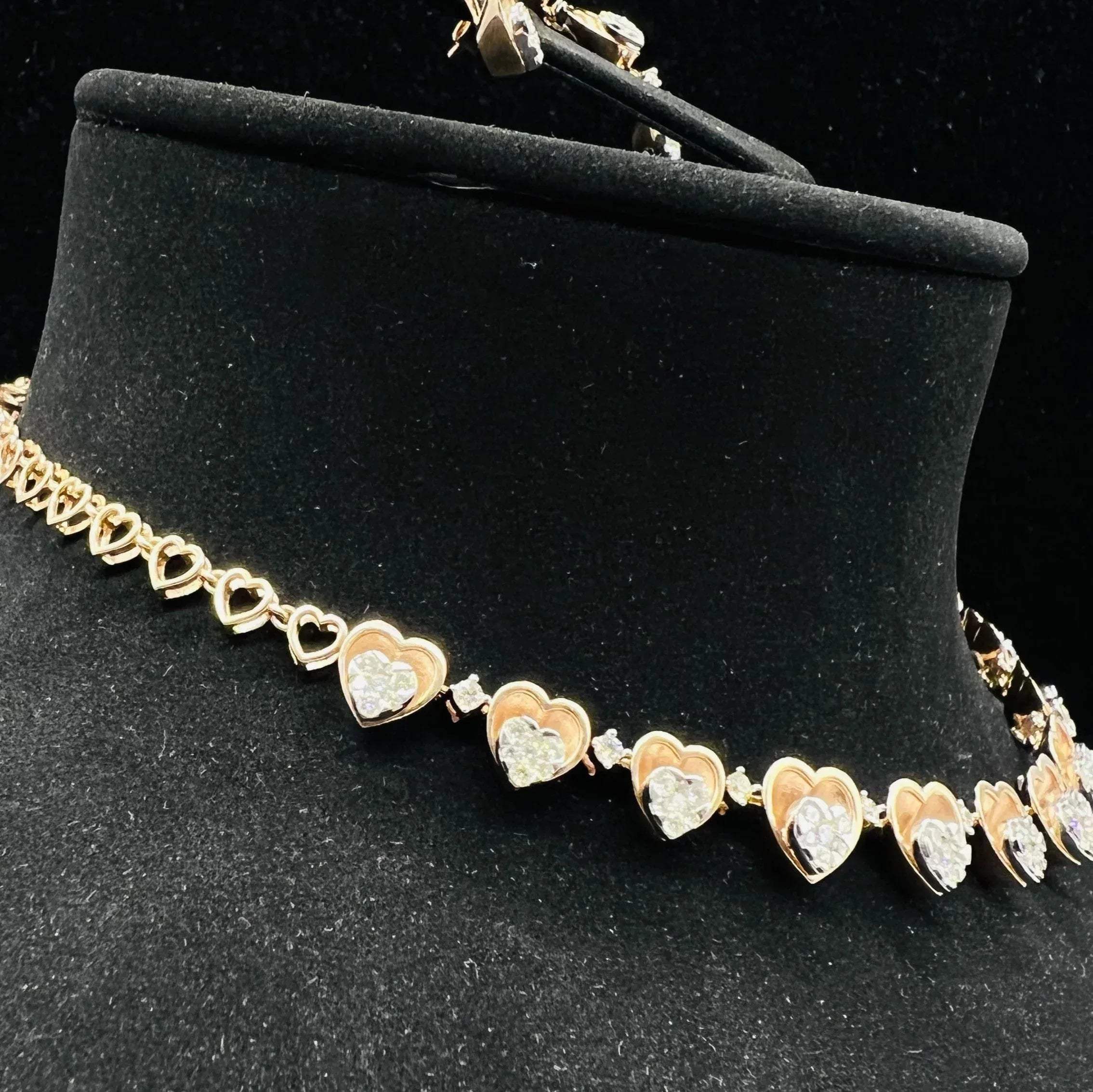 A gold necklace with round-cut diamond pendants and coordinating earrings, displayed on a black mannequin bust.