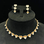 A gold necklace with round-cut diamond pendants and coordinating earrings, displayed on a black mannequin bust.