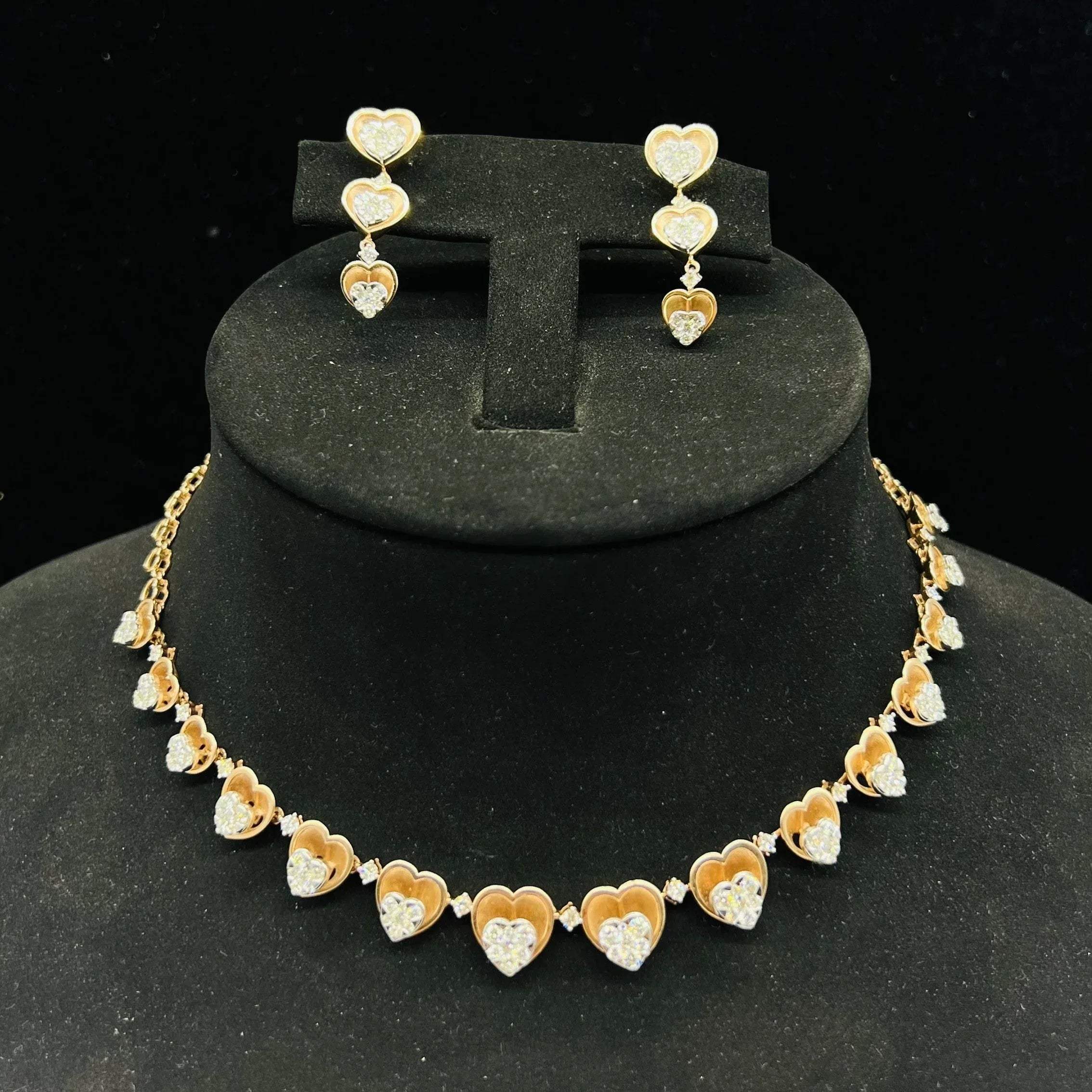 A gold necklace with round-cut diamond pendants and coordinating earrings, displayed on a black mannequin bust.