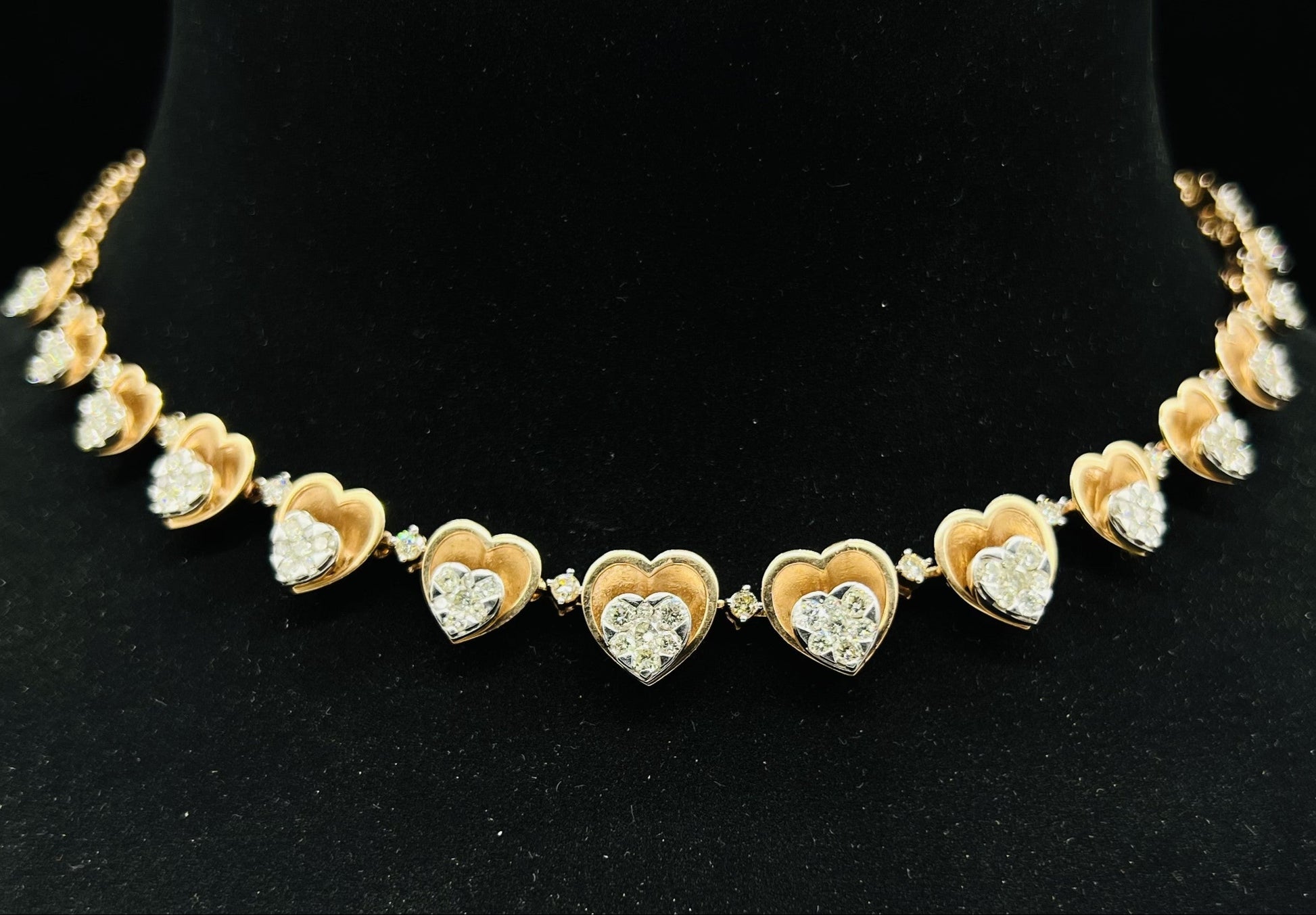 A gold necklace with round-cut diamond pendants, displayed on a black mannequin bust.