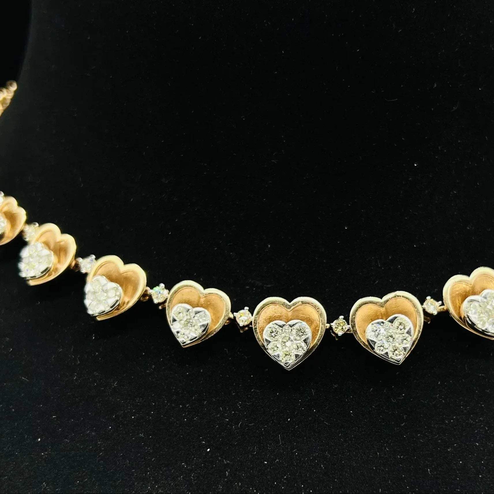 A gold necklace with round-cut diamond pendants, displayed on a black mannequin bust.