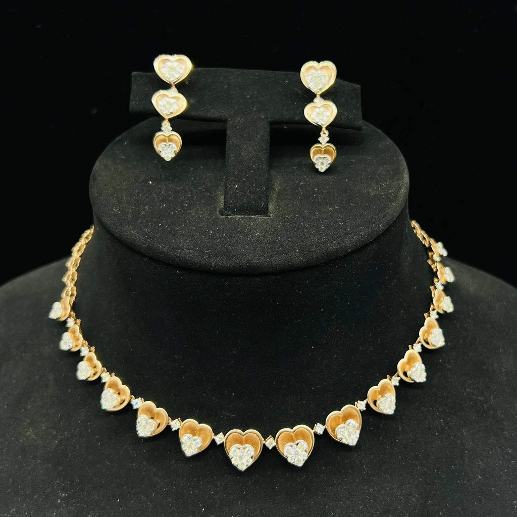 A gold necklace with round-cut diamond pendants and coordinating earrings, displayed on a black mannequin bust.
