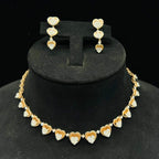 A gold necklace with round-cut diamond pendants and coordinating earrings, displayed on a black mannequin bust.