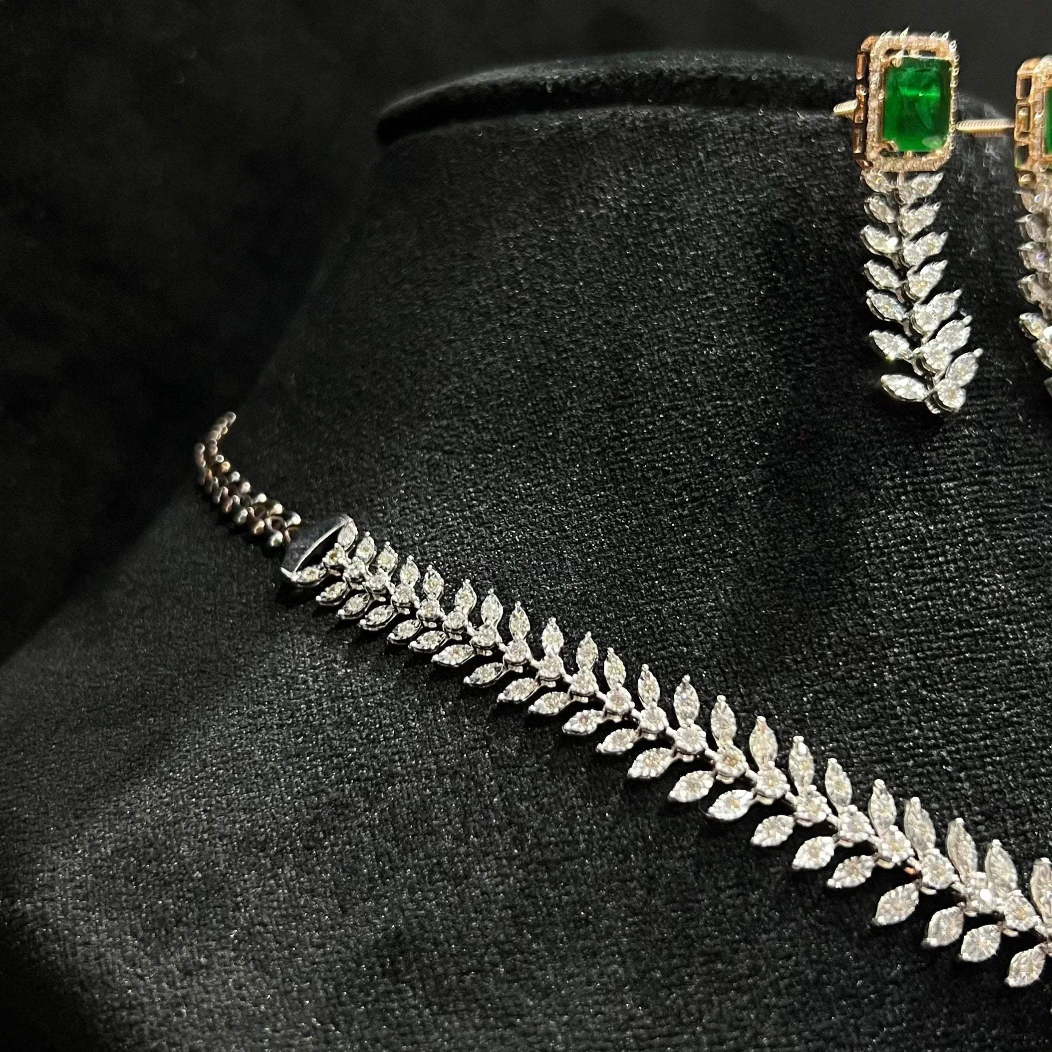 Diamond necklace set framed by diamond leaves and cascading diamond drops, paired with matching earrings on a mannequin bust from right side.