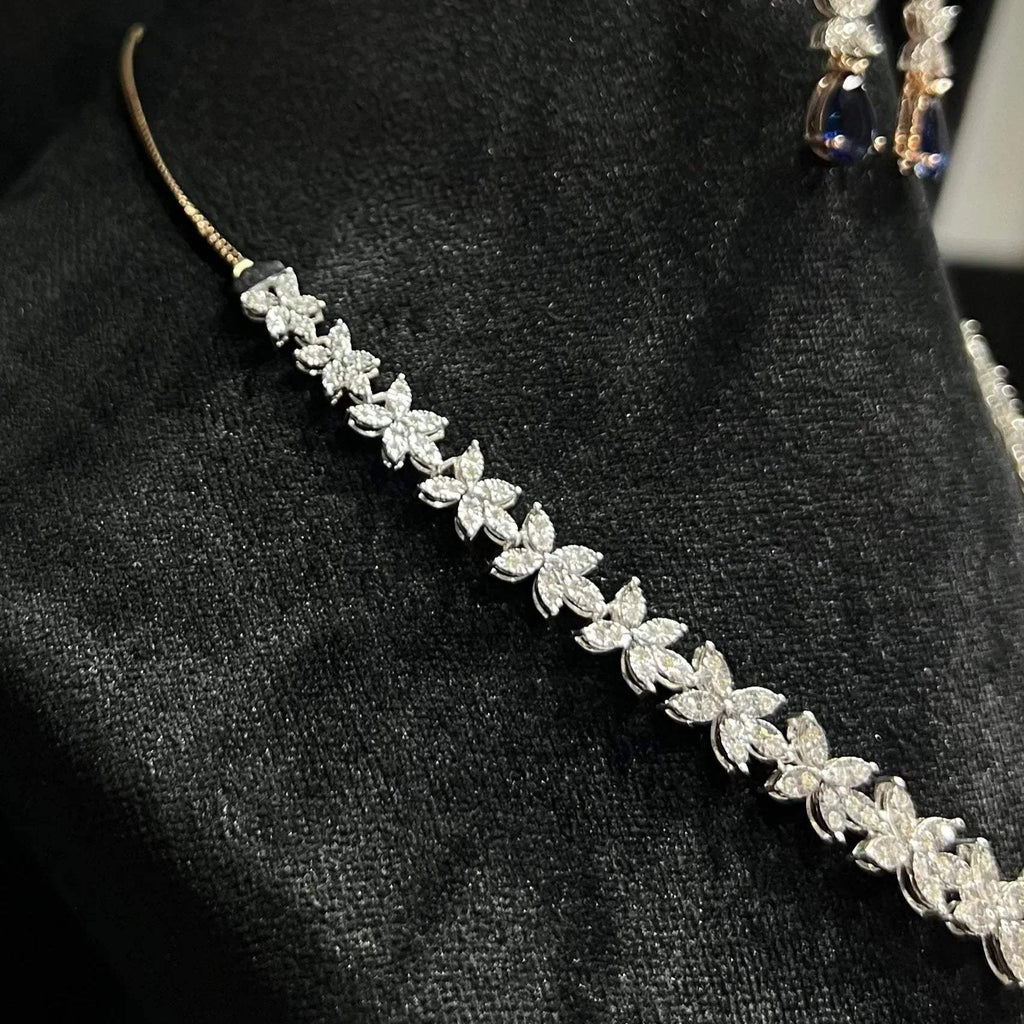 Diamond necklace set with color stone drop pendant and matching floral diamond earrings displayed on black stand from right side.