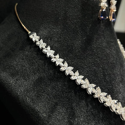 Diamond necklace set with color stone drop pendant and matching floral diamond earrings displayed on black stand from right side.