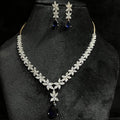 A gold diamond necklace set with matching earrings displayed on a mannequin bust, featuring a chain of gold and a series of graduated square and round cut diamonds & blue stones.