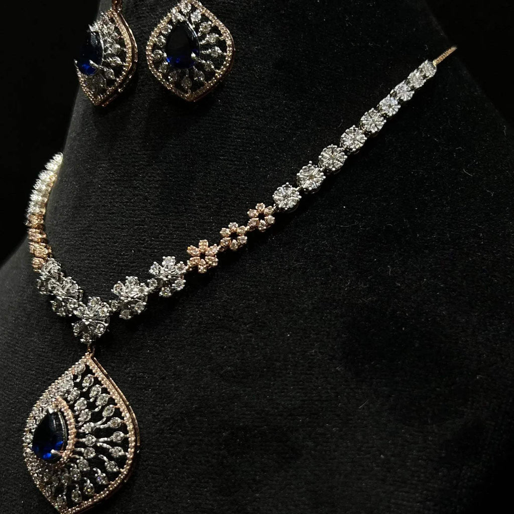 Floral design diamond necklace set with matching earrings, featuring a pear-shaped blue stone drop surrounded by natural diamonds.