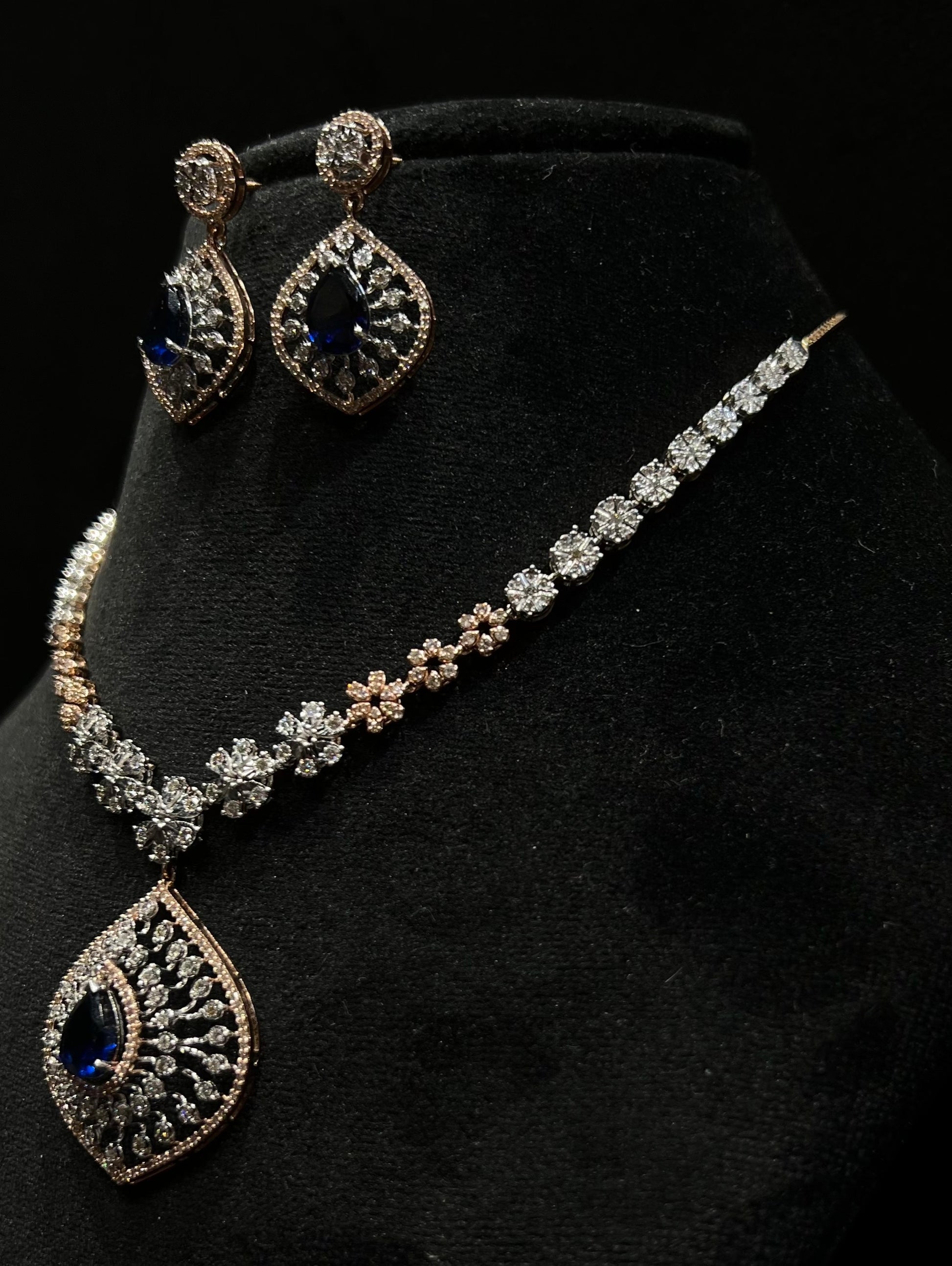 Floral design diamond necklace set with matching earrings, featuring a pear-shaped blue stone drop surrounded by natural diamonds.