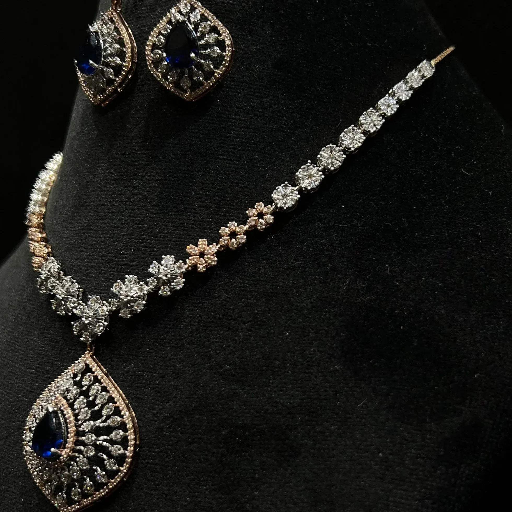 Floral design diamond necklace set with matching earrings, featuring a pear-shaped blue stone drop surrounded by natural diamonds.