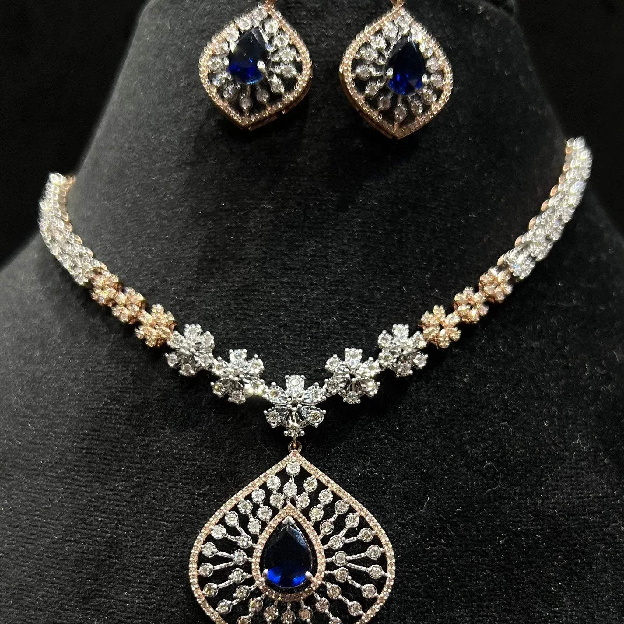 Floral design diamond necklace set with matching earrings, featuring a pear-shaped blue stones drop surrounded by natural diamonds.