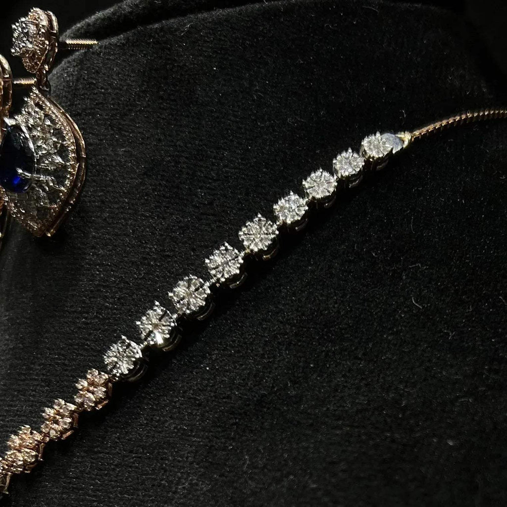 Floral design diamond necklace set with matching earrings, featuring a pear-shaped blue stone drop surrounded by natural diamonds.