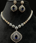 A gold diamond necklace with earrings, featuring a floral pattern and adorned with blue and clear stones.