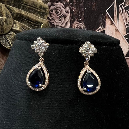 Close-up of color stone and diamond earrings from diamond necklace set with floral top design displayed on a mannequin bust.