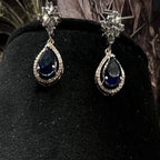 Elegant diamond necklace set with teardrop color stone pendant and matching earrings on black display