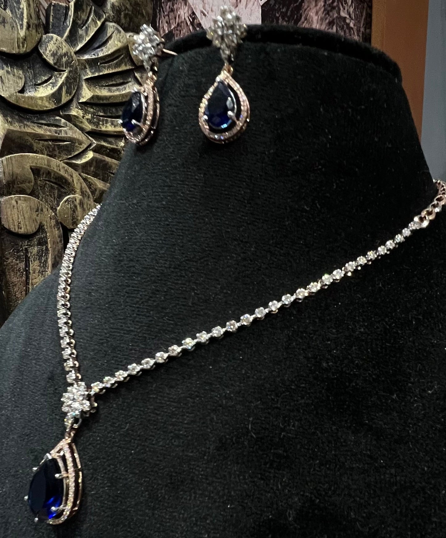 Side view of diamond necklace set featuring color stone teardrop pendant and delicate chain with matching earrings