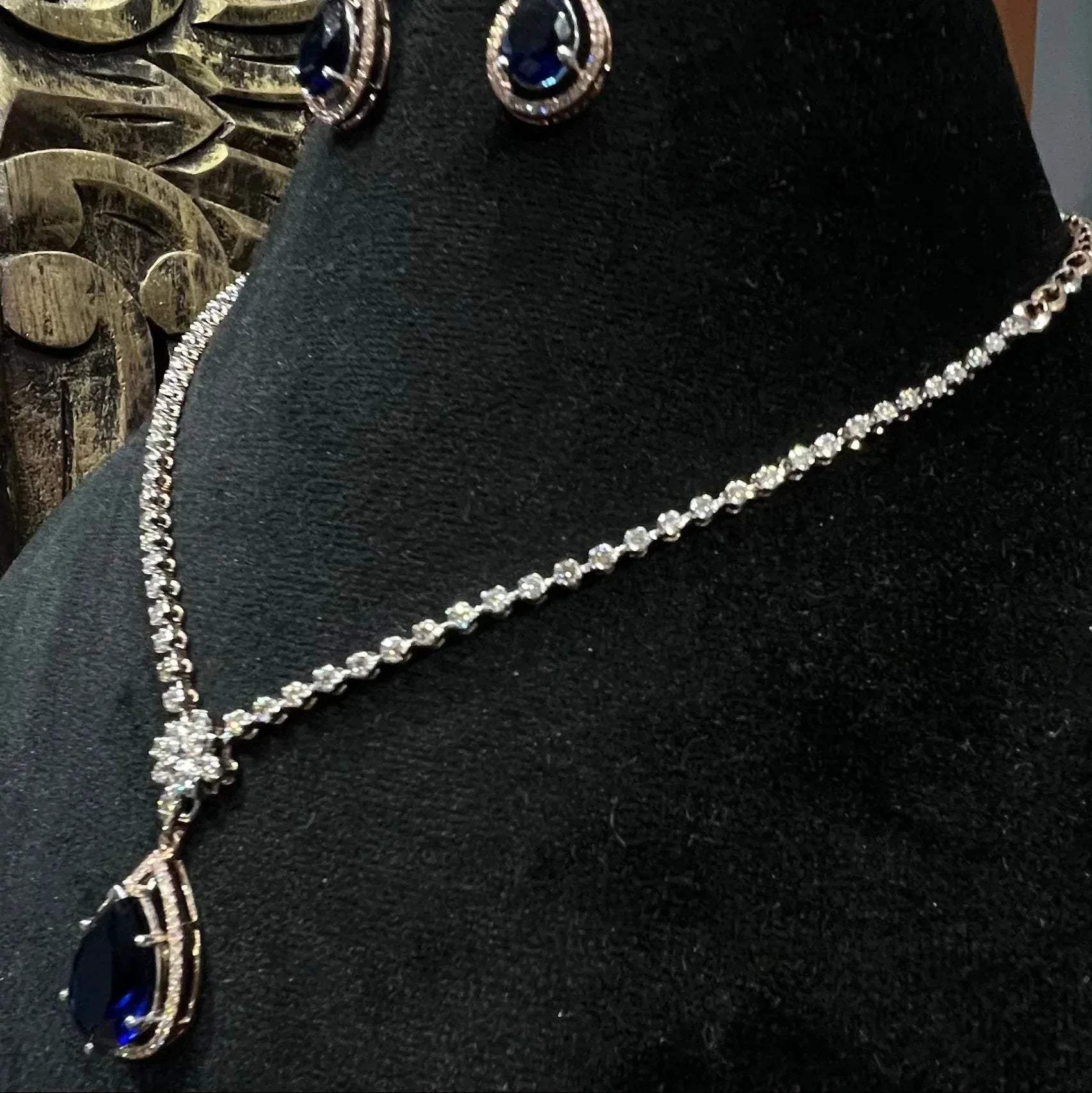 Side view of diamond necklace set featuring color stone teardrop pendant and delicate chain with matching earrings