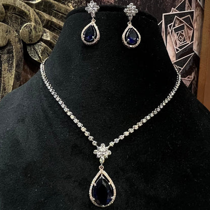 Elegant diamond necklace set with teardrop color stone pendant and matching earrings on black display