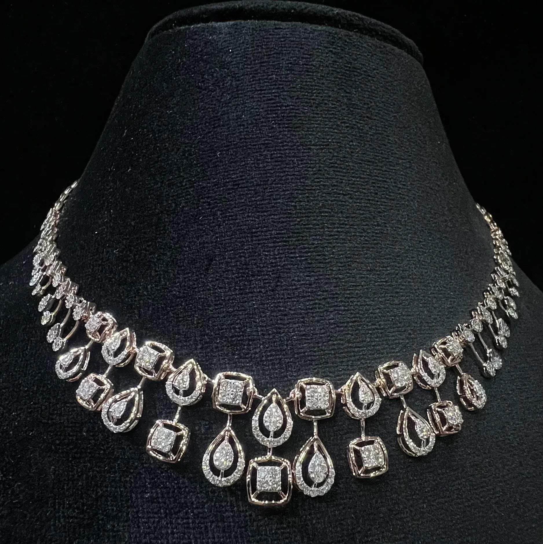 A 14K gold diamond necklace set displayed on a mannequin bust, featuring a solid gold structure with diamond encrusted in the necklace.