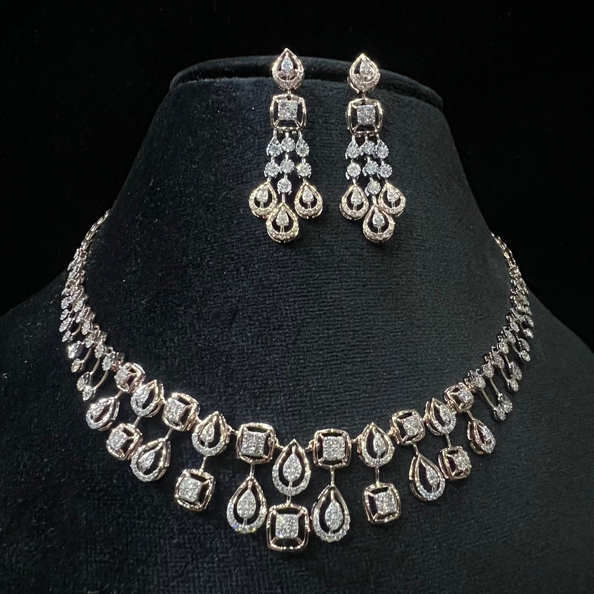 A gold diamond necklace and earrings set displayed on a mannequin bust, featuring a solid gold structure with diamond encrusted in the earrings and necklace.