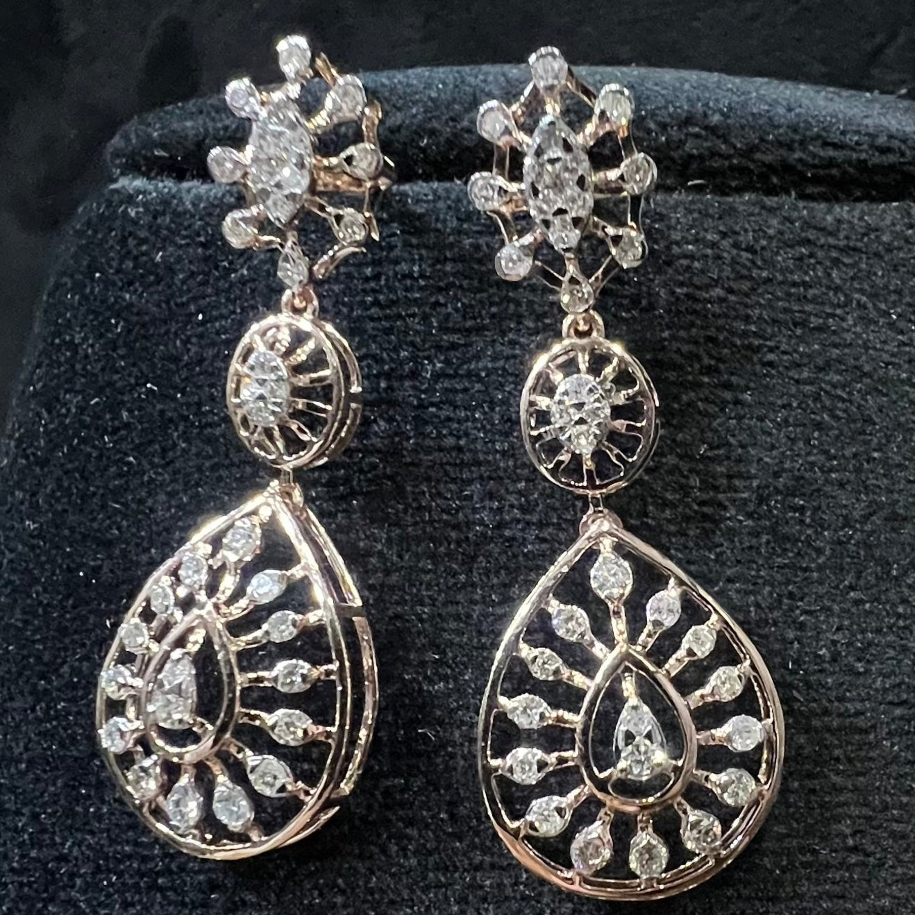 Elegant teardrop-shaped diamond  earrings with floral-inspired motifs displayed on a black background.