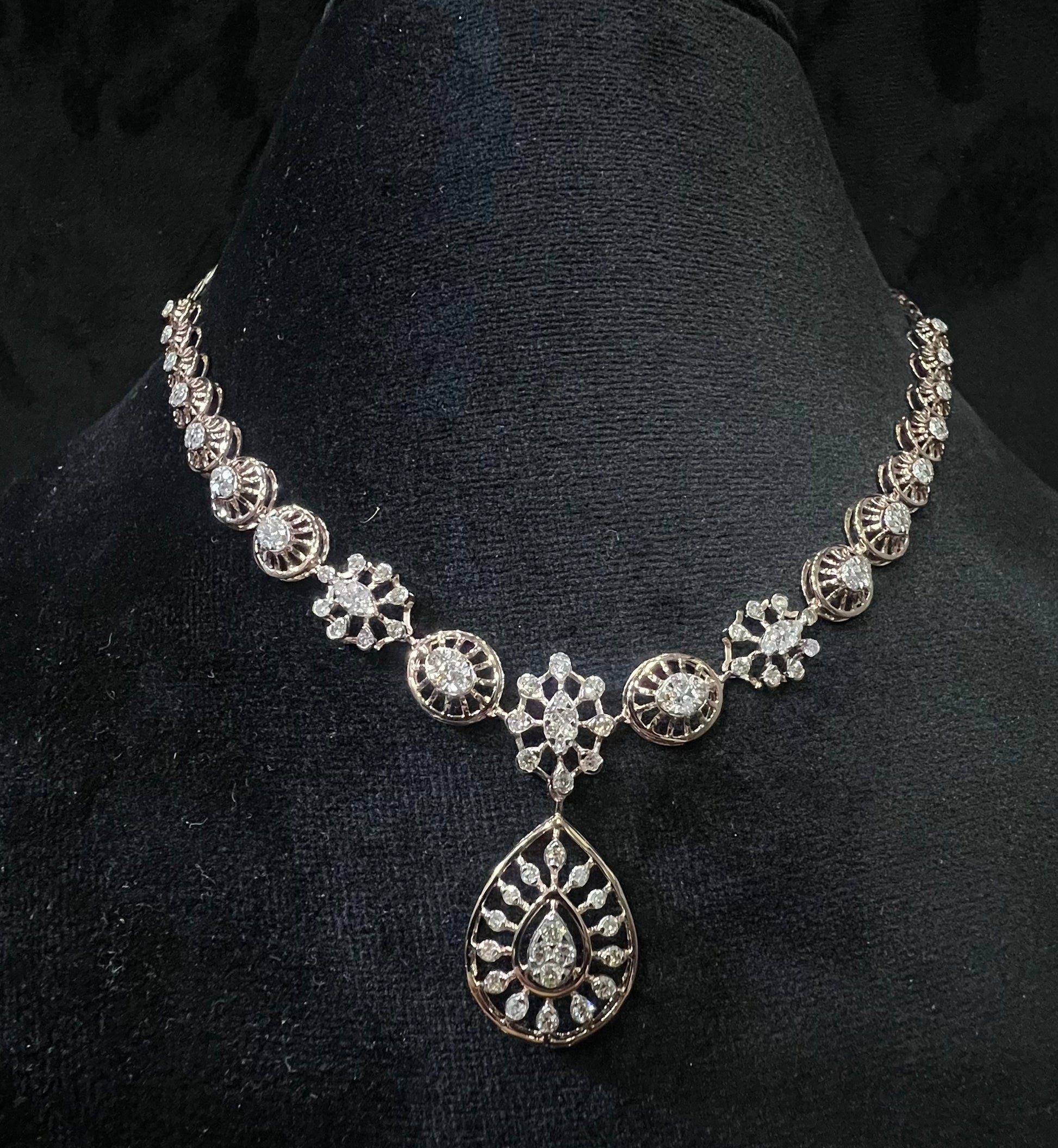 Elegant teardrop-shaped diamond  necklace with floral-inspired motifs displayed on a black background.