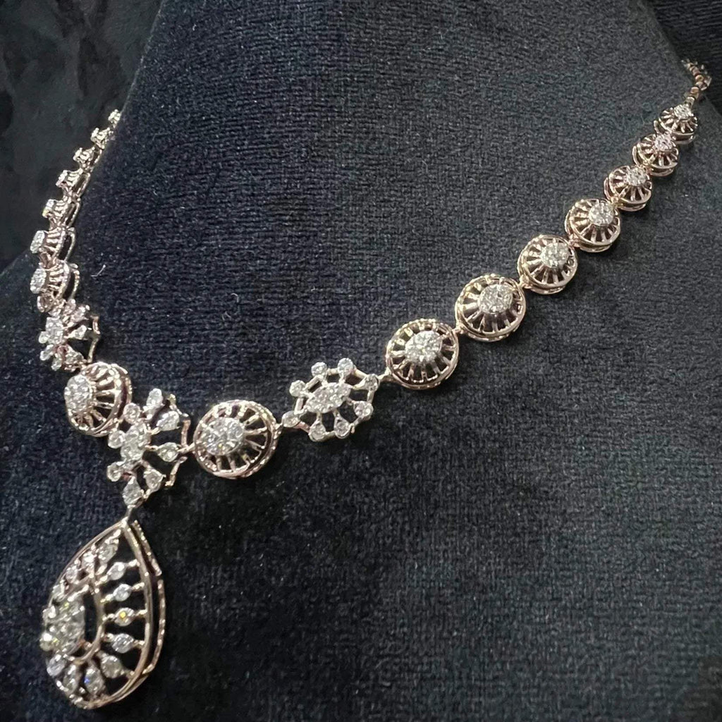 Elegant teardrop-shaped diamond necklace set with floral-inspired motifs displayed on a black background.