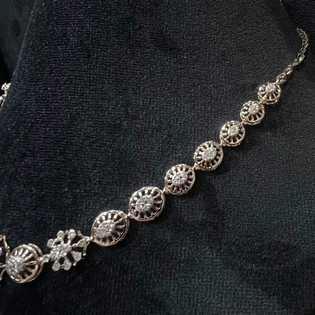 Elegant teardrop-shaped diamond necklace set with floral-inspired motifs displayed on a black background.