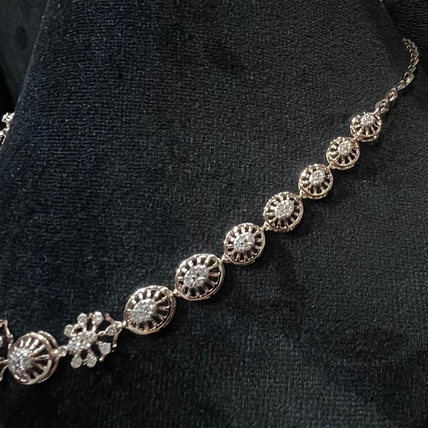 Elegant teardrop-shaped diamond necklace set with floral-inspired motifs displayed on a black background.