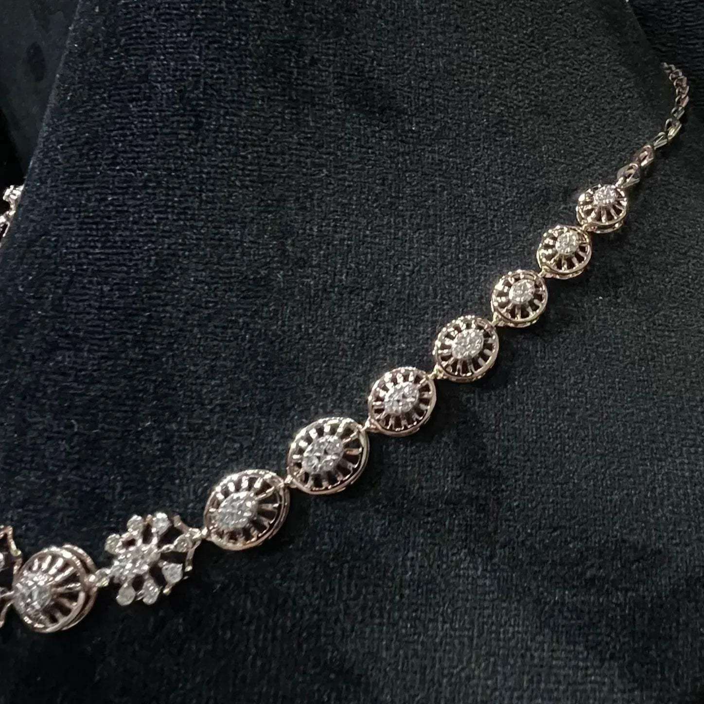 Elegant teardrop-shaped diamond necklace set with floral-inspired motifs displayed on a black background.