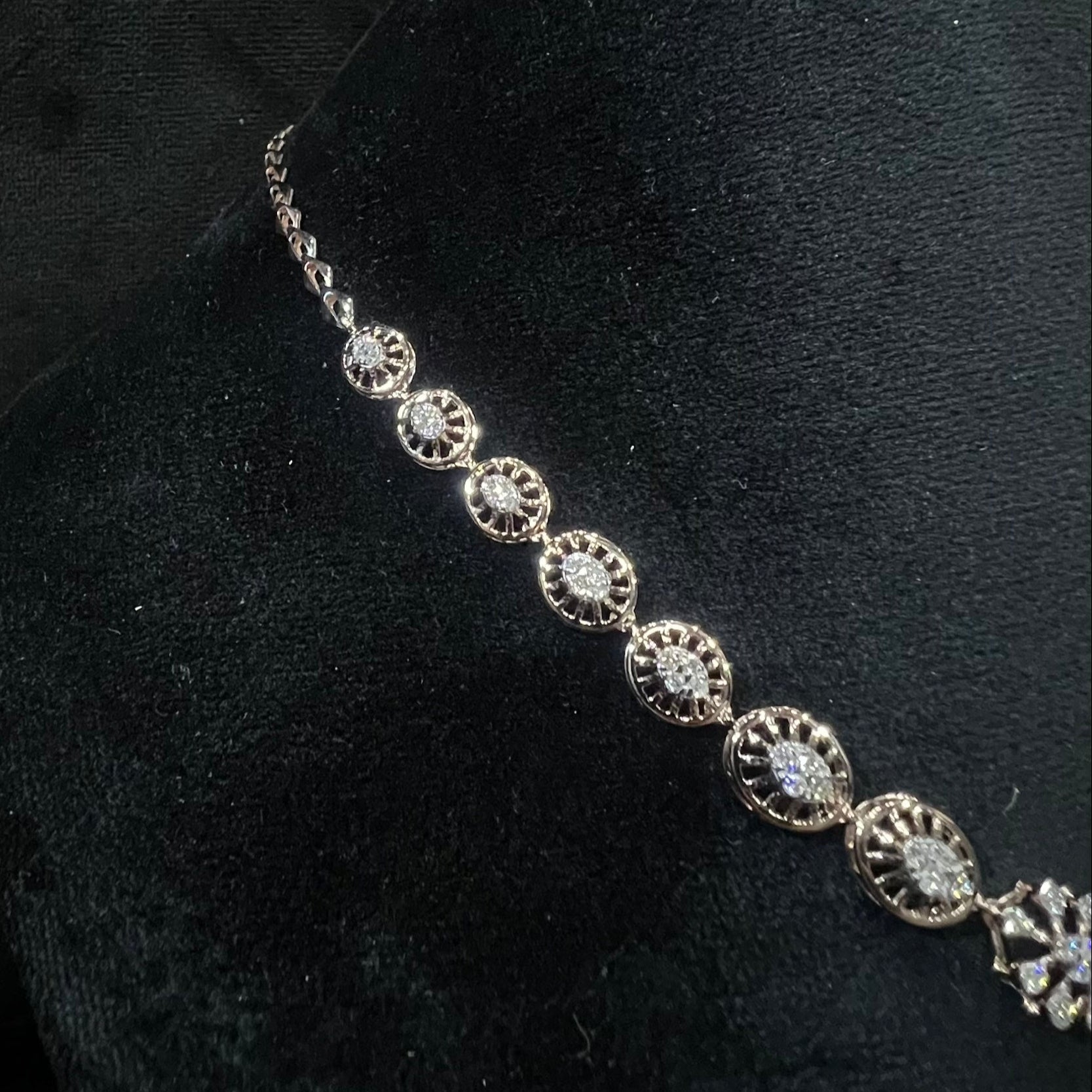 Elegant teardrop-shaped diamond necklace set with floral-inspired motifs displayed on a black background.