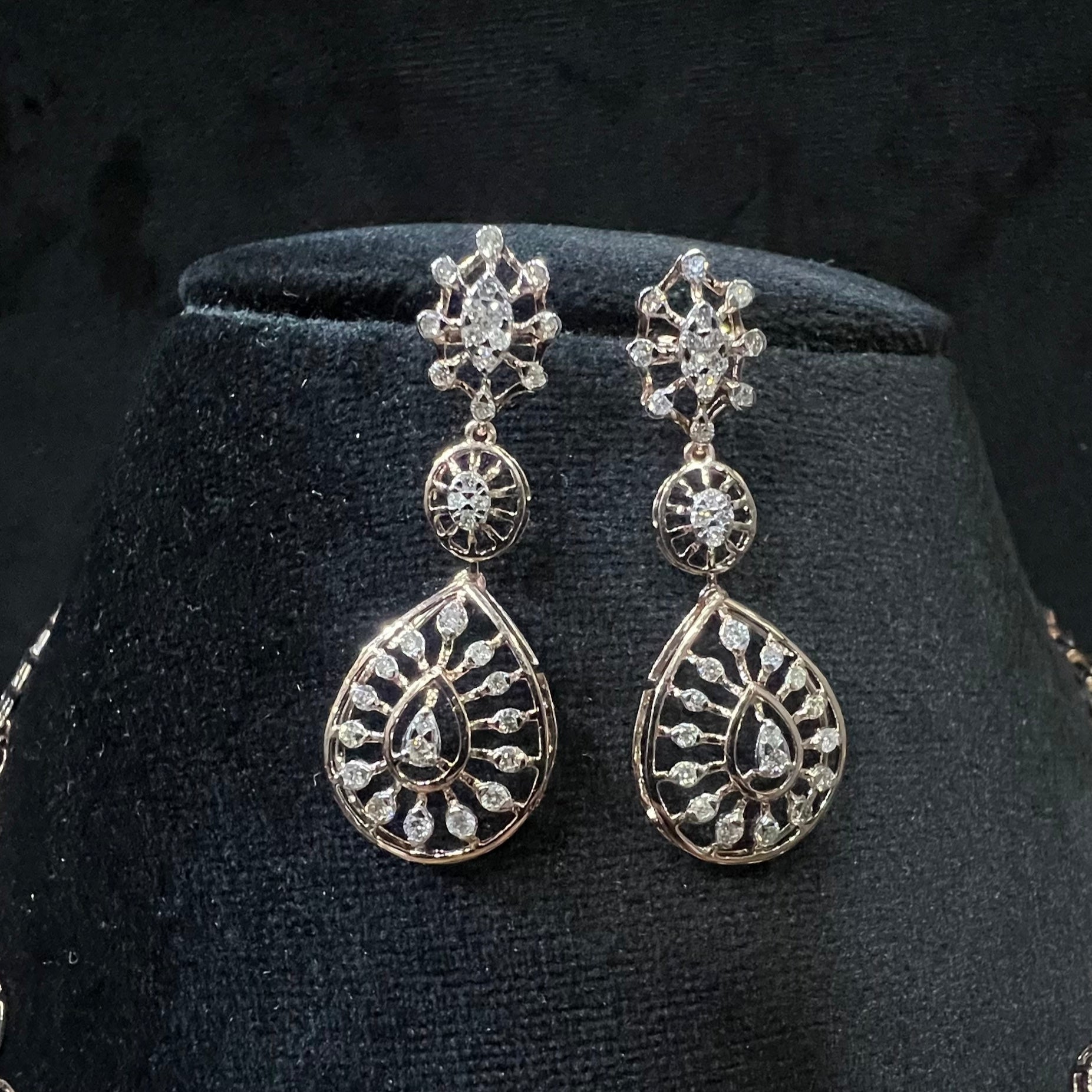 Elegant teardrop-shaped diamond  earrings with floral-inspired motifs displayed on a black background.