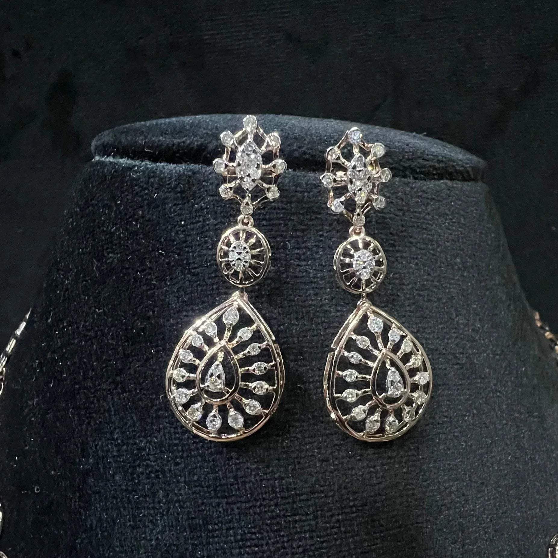 Elegant teardrop-shaped diamond  earrings with floral-inspired motifs displayed on a black background.