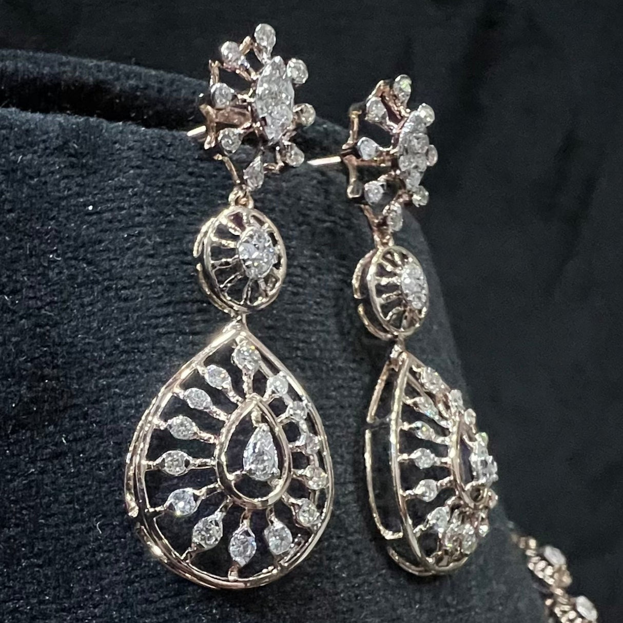 Elegant teardrop-shaped diamond  earrings with floral-inspired motifs displayed on a black background.