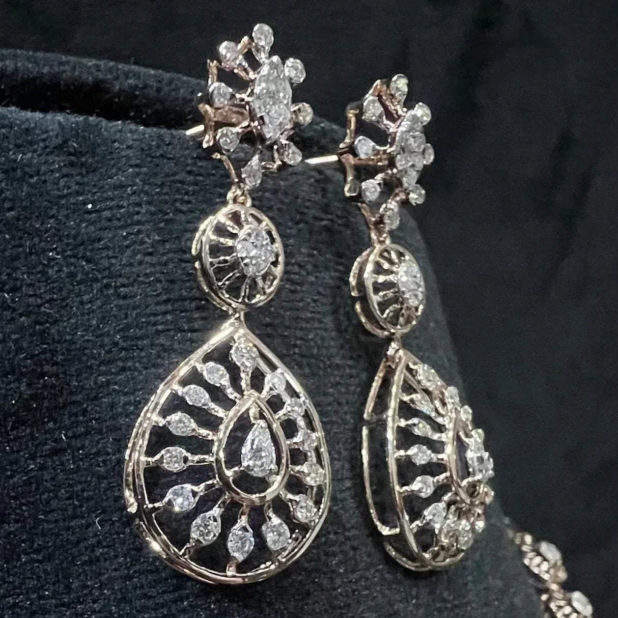 Elegant teardrop-shaped diamond  earrings with floral-inspired motifs displayed on a black background.