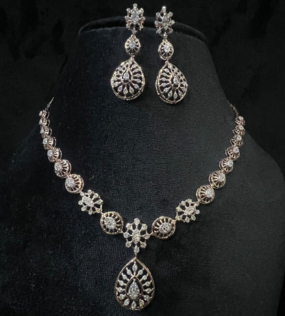 Elegant teardrop-shaped diamond necklace set with floral-inspired motifs and matching earrings displayed on a black background.