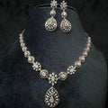 A gold diamond necklace with a floral pattern and a pair of matching earrings, displayed on a black mannequin bust.