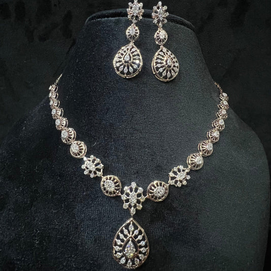 A gold diamond necklace with a floral pattern and a pair of matching earrings, displayed on a black mannequin bust.