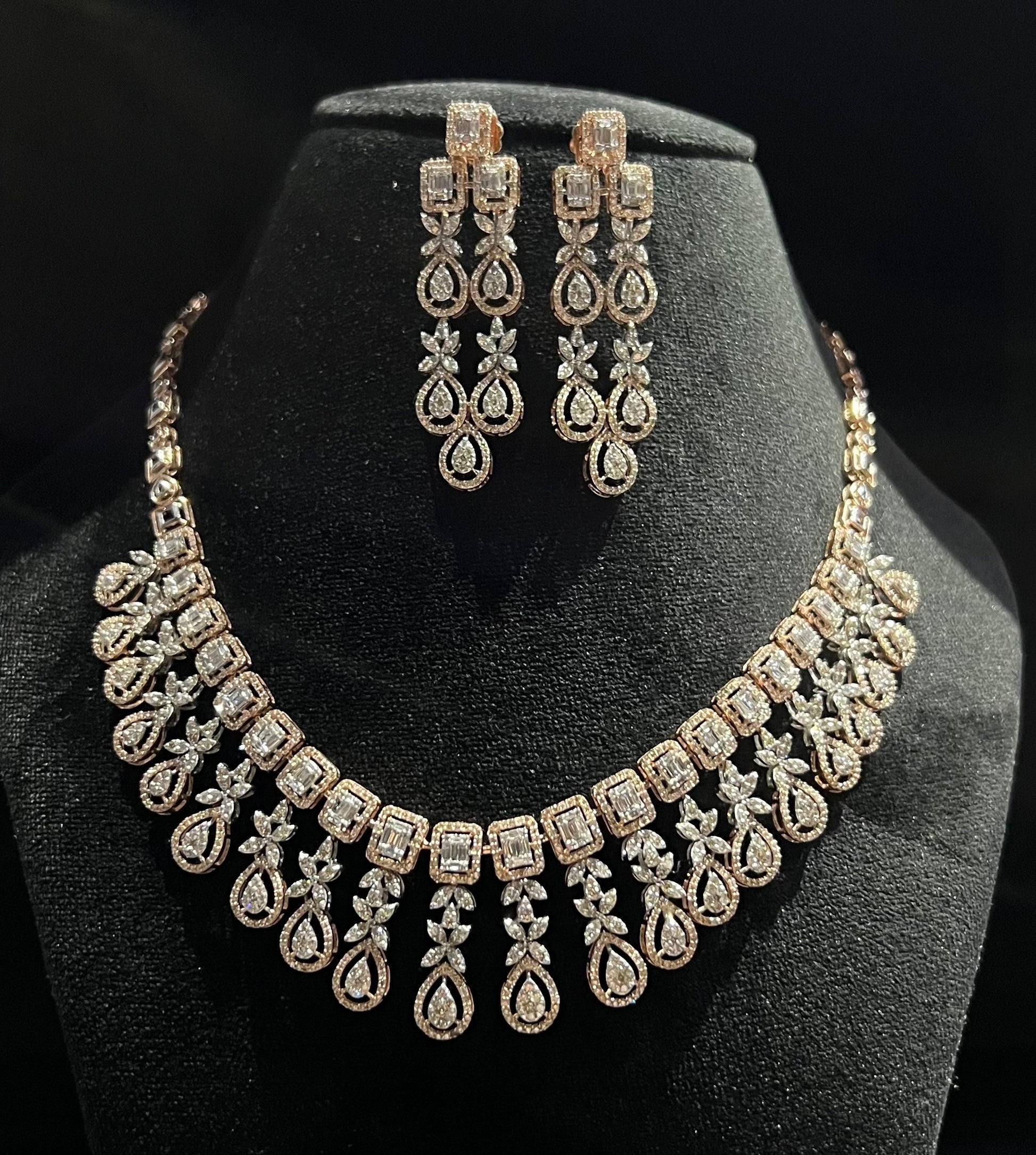Luxury floral motif diamond necklace set with matching drop earrings on a mannequin bust.