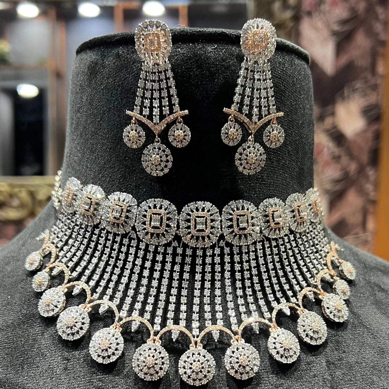 A gold diamond choker necklace with a matching set of earrings, adorned with brilliant cut diamonds, displayed on a mannequin.