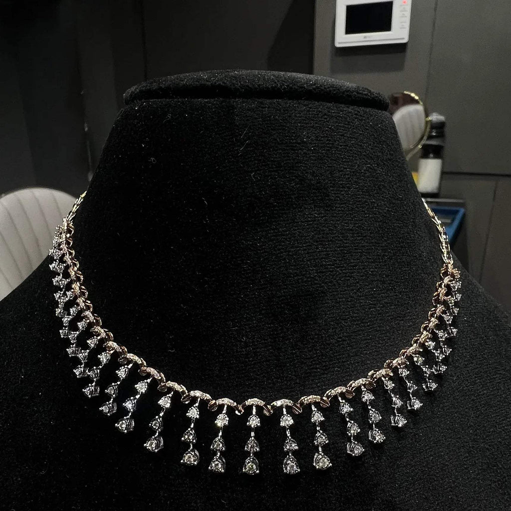 A gold diamond necklace attached to the neckline, set on a black mannequin.