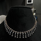 A gold diamond necklace attached to the neckline, set on a black mannequin.