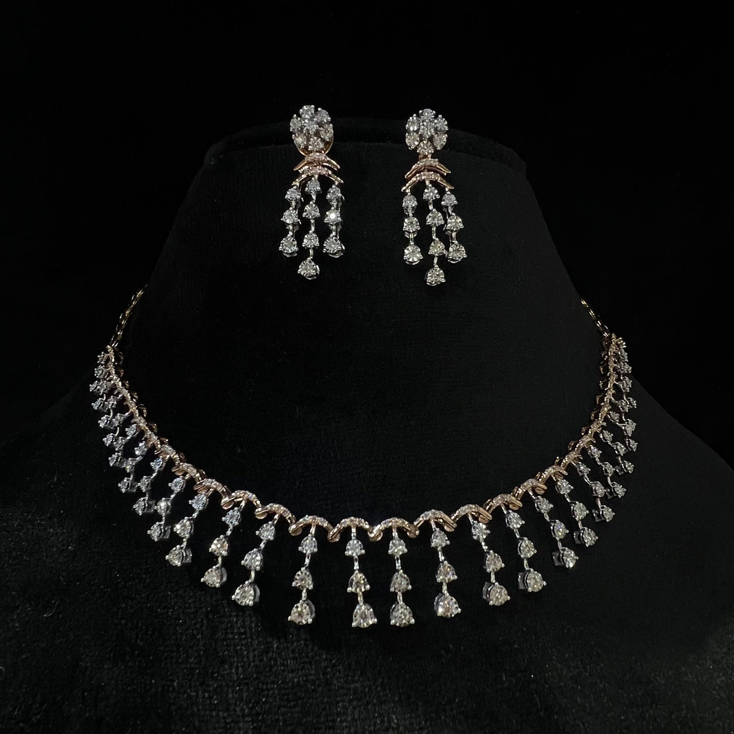 A gold diamond necklace with a series of round and marquise shaped earrings attached to the neckline, set on a black mannequin.