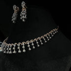 A gold diamond necklace with a series of round and marquise shaped earrings attached to the neckline, set on a black mannequin.