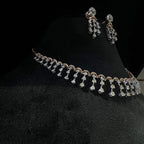 A gold diamond necklace with a series of round and marquise shaped earrings attached to the neckline, set on a black mannequin.