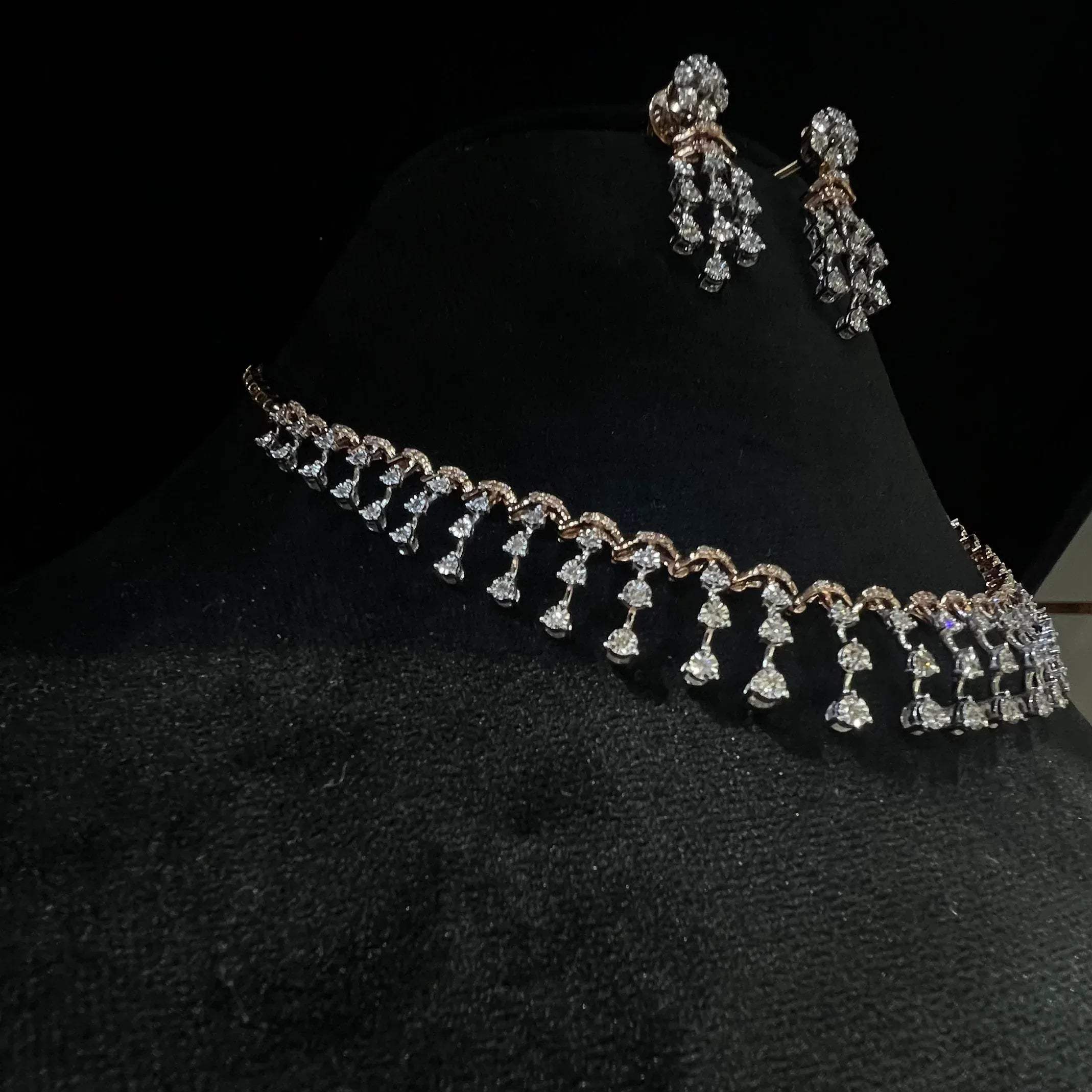 A gold diamond necklace with a series of round and marquise shaped earrings attached to the neckline, set on a black mannequin.