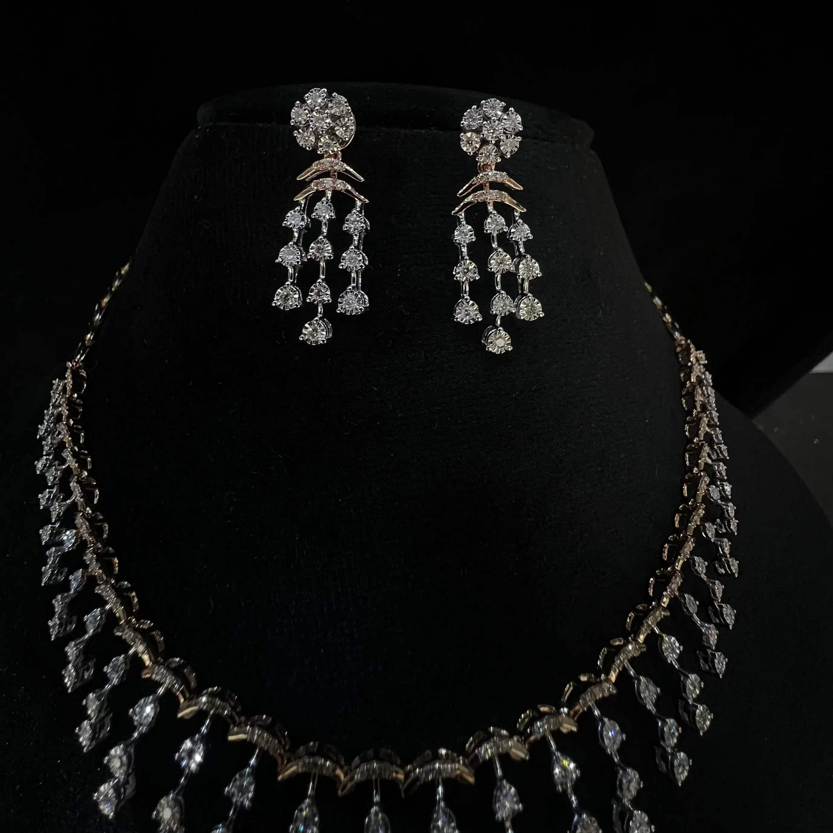 A gold diamond necklace with a series of round and marquise shaped earrings attached to the neckline, set on a black mannequin.
