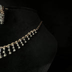 A gold diamond necklace with a series of round and marquise shaped earrings attached to the neckline, set on a black mannequin.